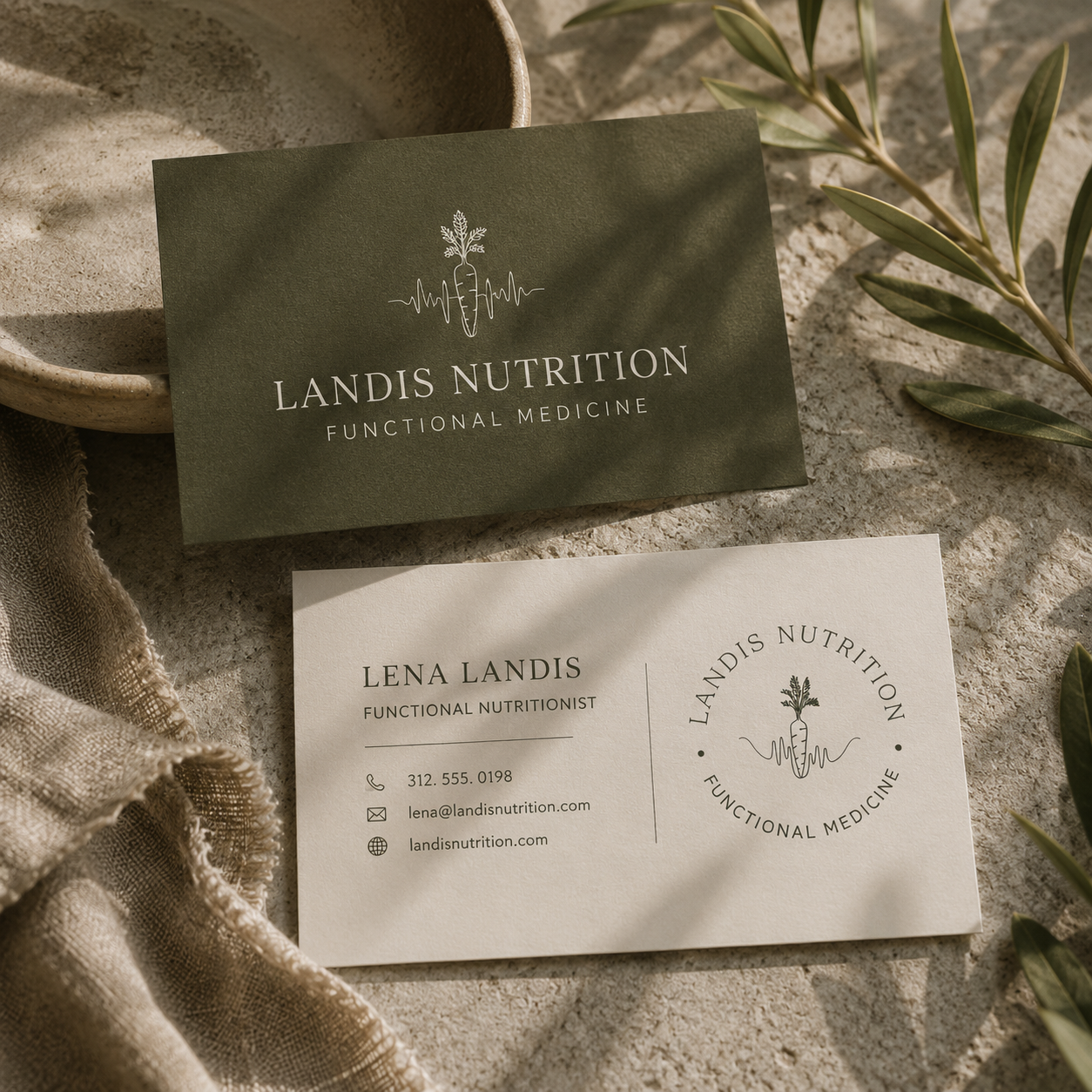 Square editorial mockup of Landis Nutrition business cards on a warm textured surface. A deep olive card features the cream Landis Nutrition logo and “Functional Medicine,” while an ivory card displays Lena Landis’s name, functional nutritionist title, contact information, and the circular carrot-and-heartbeat logo. Olive branches, linen, soft sunlight, and natural shadows create an earthy, refined wellness aesthetic.